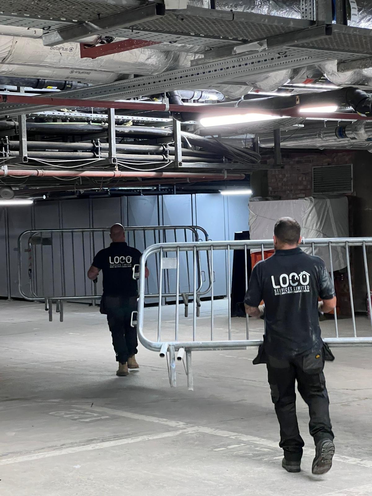 LOCO team members carrying site barriers through a commercial space