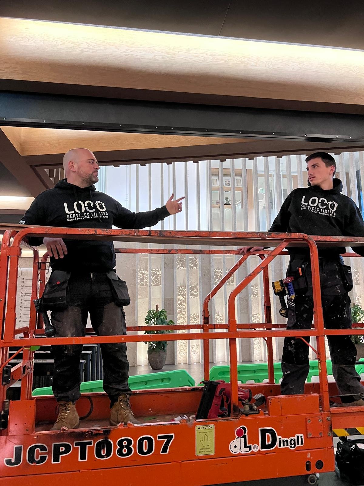 Two LOCO team members discussing work from a raised access platform
